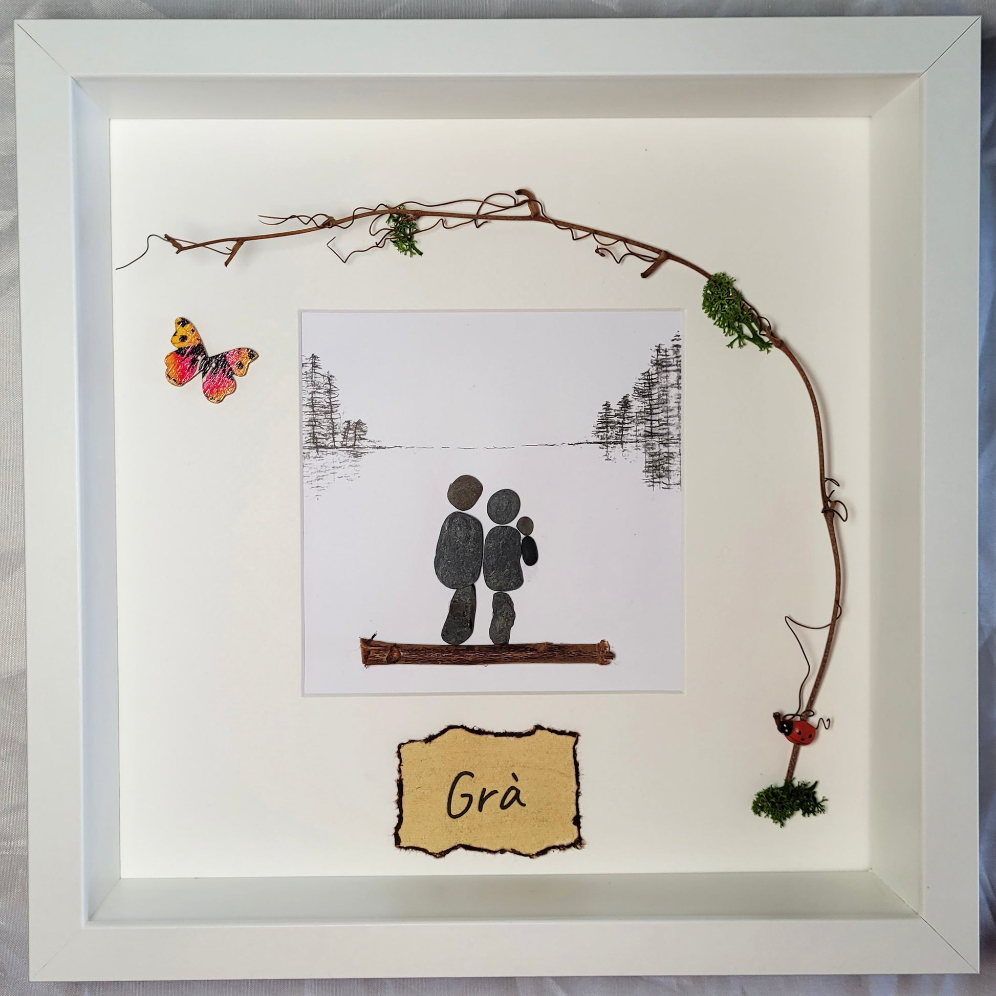 A pebble couple and their child in a white frame. Love